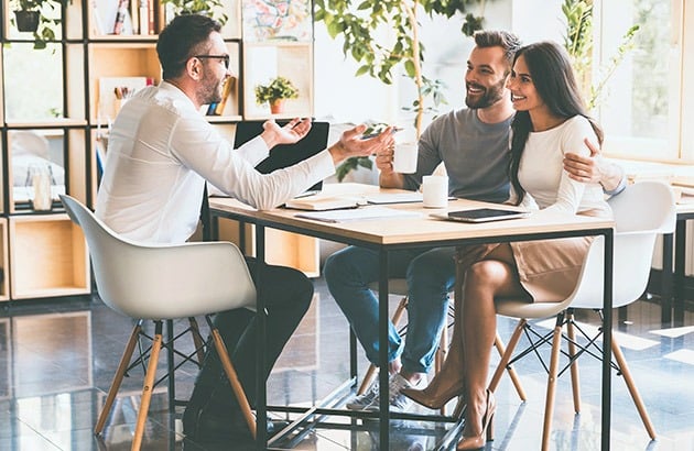 A couple meets with an advisor at a table in a bright office.