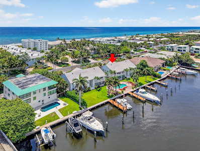 Waterfront home with a pool and private dock, viewed from above with the ocean beyond.