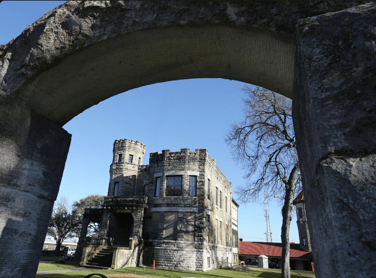 Cottonland Castle in Waco, framed by a stone arch, with crenellated parapets and a round turret.