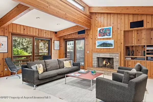 Living room with vaulted wood ceiling, stone fireplace, and gray seating.