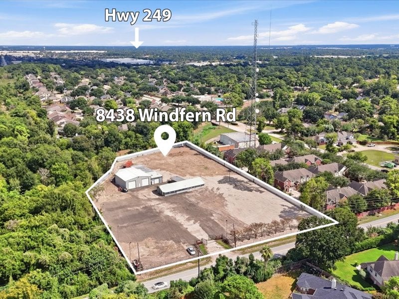 Aerial view of a cleared parcel outlined among trees and nearby homes.