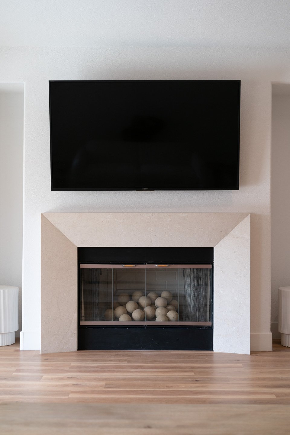 Living room fireplace with a pale stone surround and wall-mounted television.