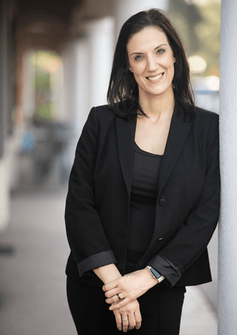 Marcia Werner in a black business suit, smiling with her hands clasped.