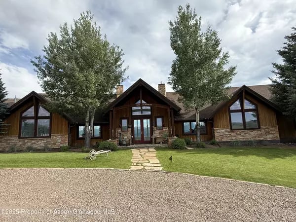 Home with dark wood siding, stone accents, and a stone walkway across the front lawn.