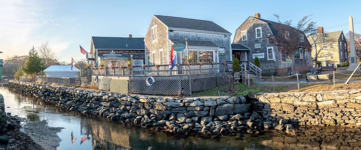 Waterfront village shops and homes stand above a stone-lined inlet.