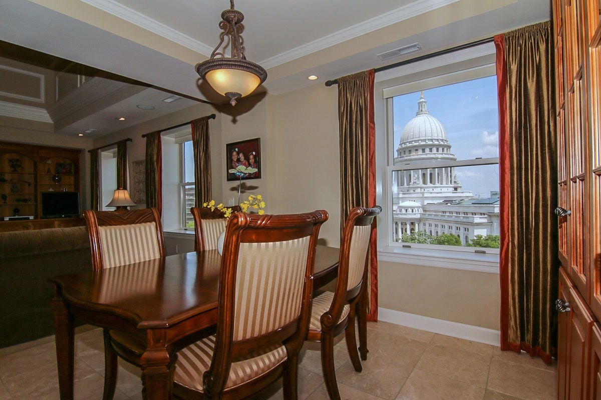 Dining room with a dark wood table and striped chairs, overlooking a domed capitol building.