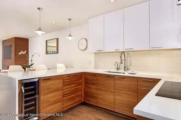 Modern kitchen with warm wood cabinets, white countertops, and a breakfast bar.