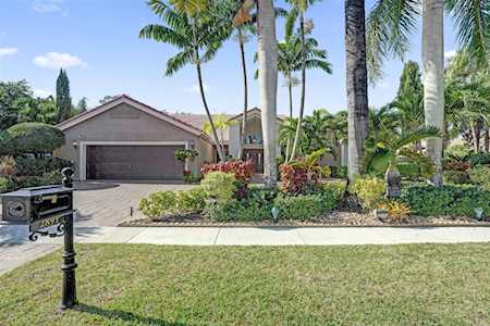 Home with a two-car garage, palm trees, landscaped yard, and mailbox by the sidewalk.
