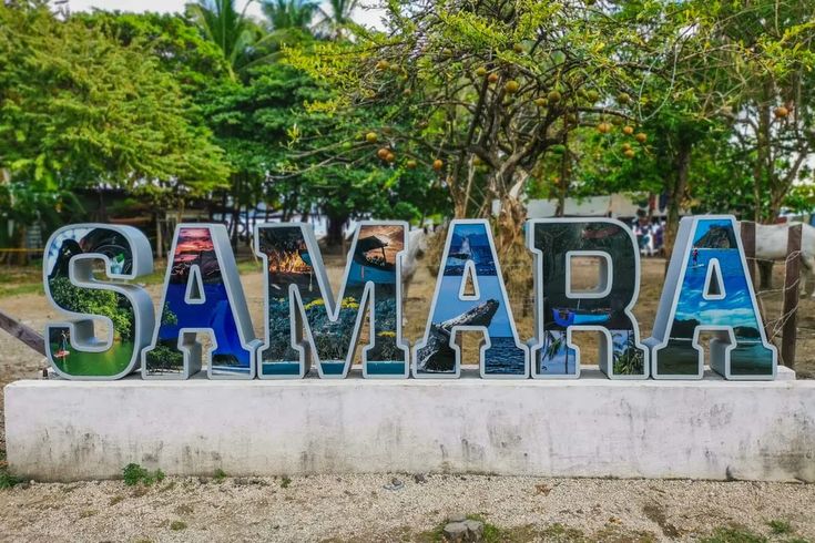 SAMARA sign with colorful photo-filled letters beneath leafy trees.