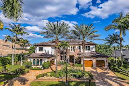 Mediterranean-style two-story home with a tiled roof, palm trees, and two garage doors.