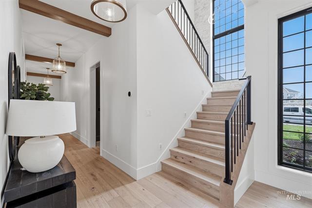 Entry foyer with a wood staircase, black railing, and tall grid windows.