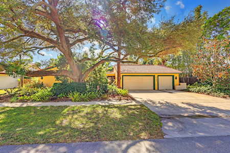 Home exterior with a two-car garage, broad driveway, and large mature shade tree.