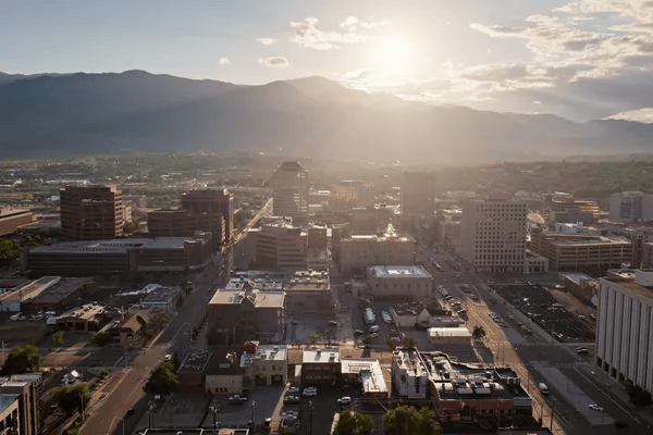 Downtown buildings and streets with a mountain range in the distance at golden hour.