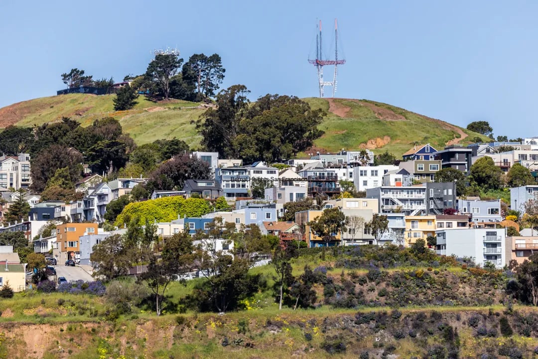 A view of homes on a hillside in Bernal Heights, San Francisco, with the Sutro Tower visible in the distance.