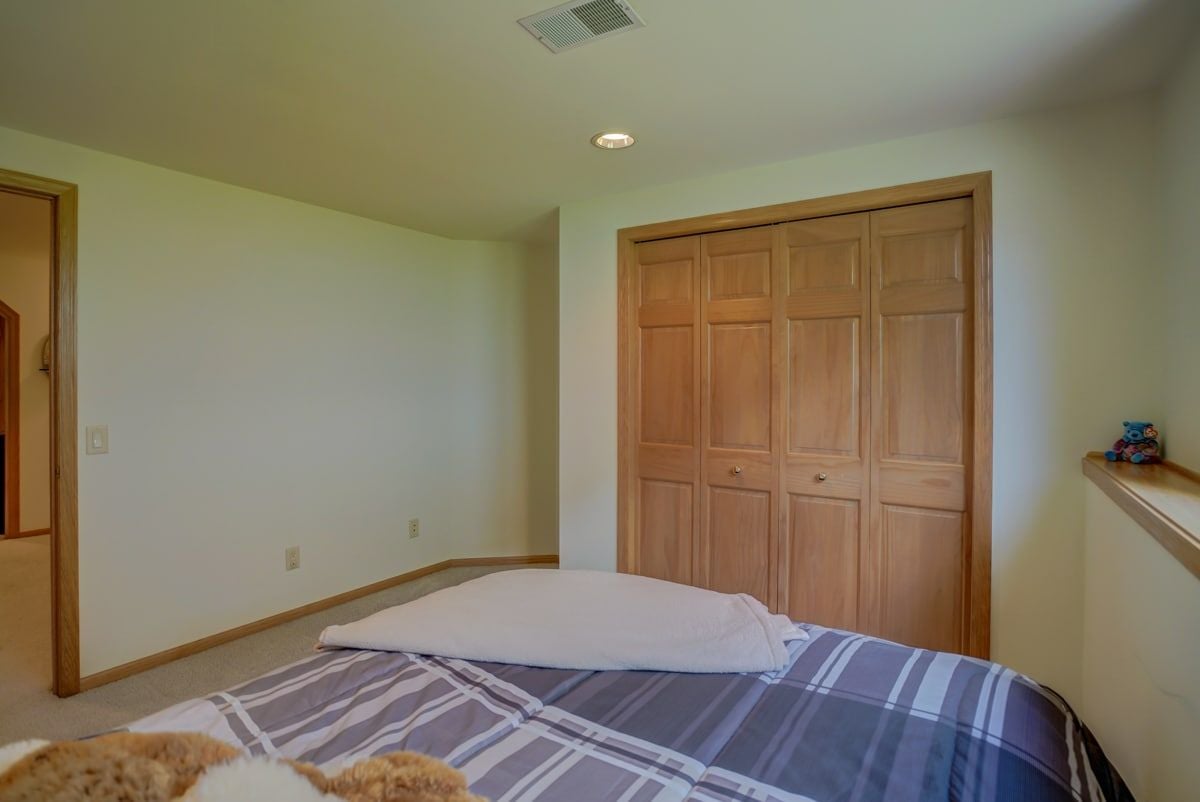 Bedroom with a striped bedspread and large wooden closet doors.