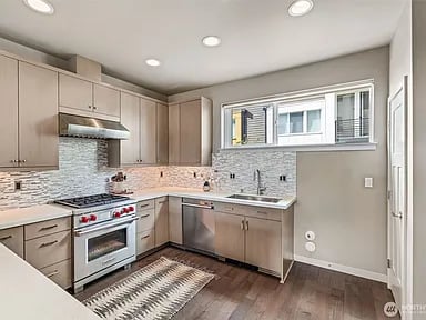 Kitchen with taupe cabinetry, stainless-steel appliances, mosaic backsplash, and a wide horizontal window.