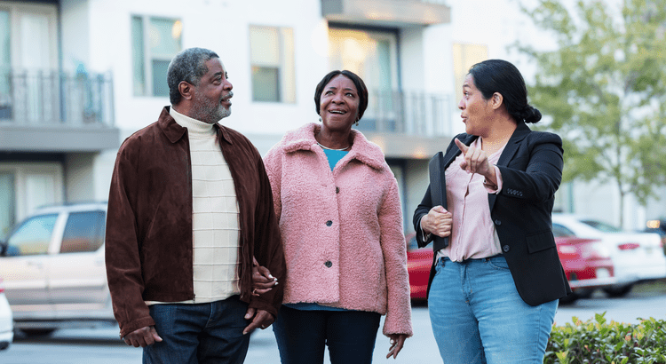 Three individuals engaged in conversation with a real estate agent, discussing property options and market insights.