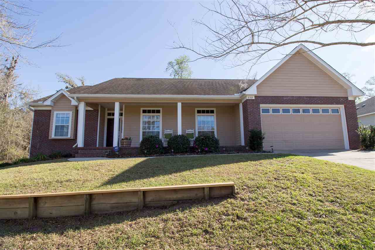 A brick home surrounded by a spacious yard and a driveway, showcasing a welcoming and well-maintained exterior.