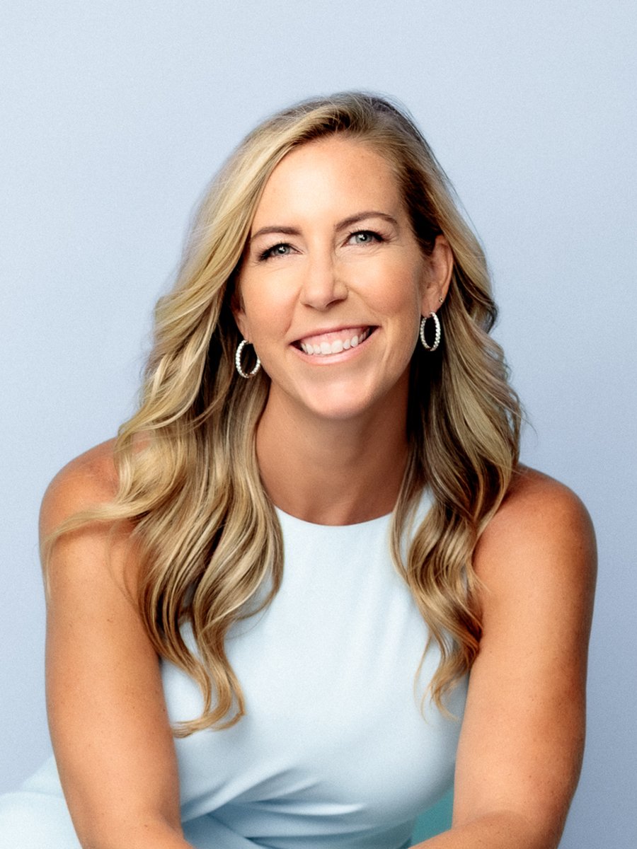 Alex Wilbrett, smiling with long blonde hair and wearing a white sleeveless top.
