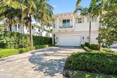 White two-story home with a broad driveway, double garage, and palm-lined landscaping.
