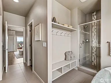 Bathroom with a glass shower and built-in bench and cubbies beside a hallway leading to a bedroom.