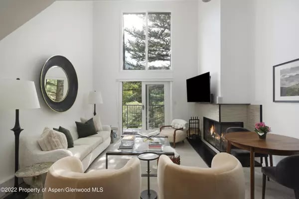 Living room with tall windows, a white sofa, and a corner fireplace.