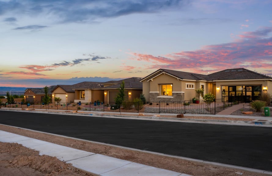 Single-story stucco homes with tile roofs along a residential street at sunset.