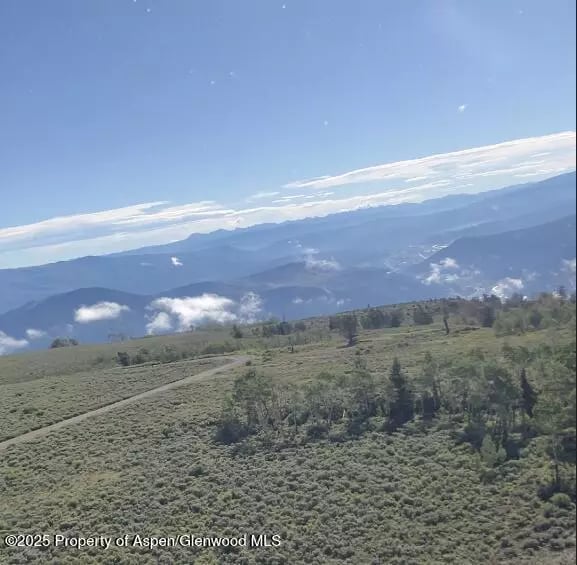 Mountain ranges and scrub-covered hills beneath a bright blue sky.