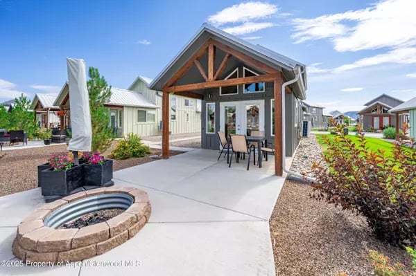 Covered courtyard pavilion with outdoor dining table, circular fire pit, and landscaped planters.