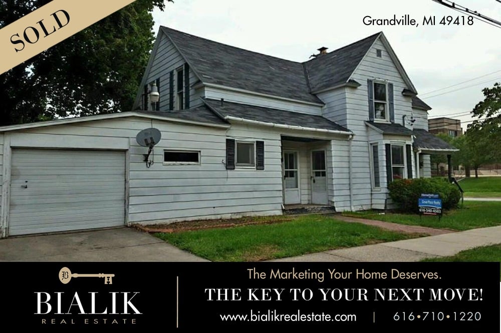 White two-story Grandville home with an attached garage, marked sold.