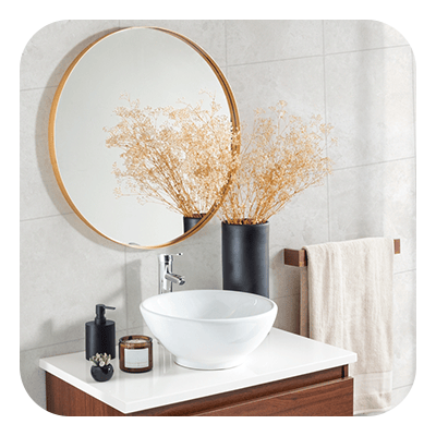 Bathroom vanity with a white vessel sink, round gold-tone mirror, and wood cabinetry.