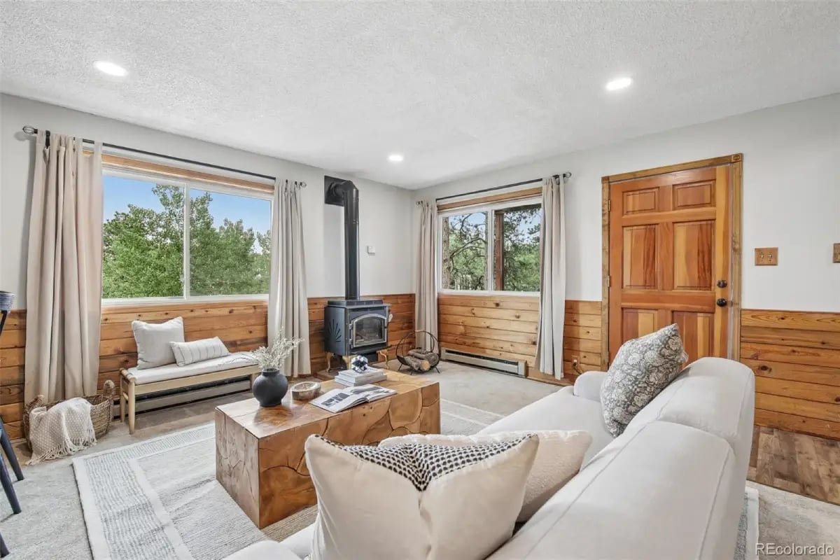 Cozy living room with a wood-burning stove, natural wood paneling, and forest views at 278 Overlook Drive.