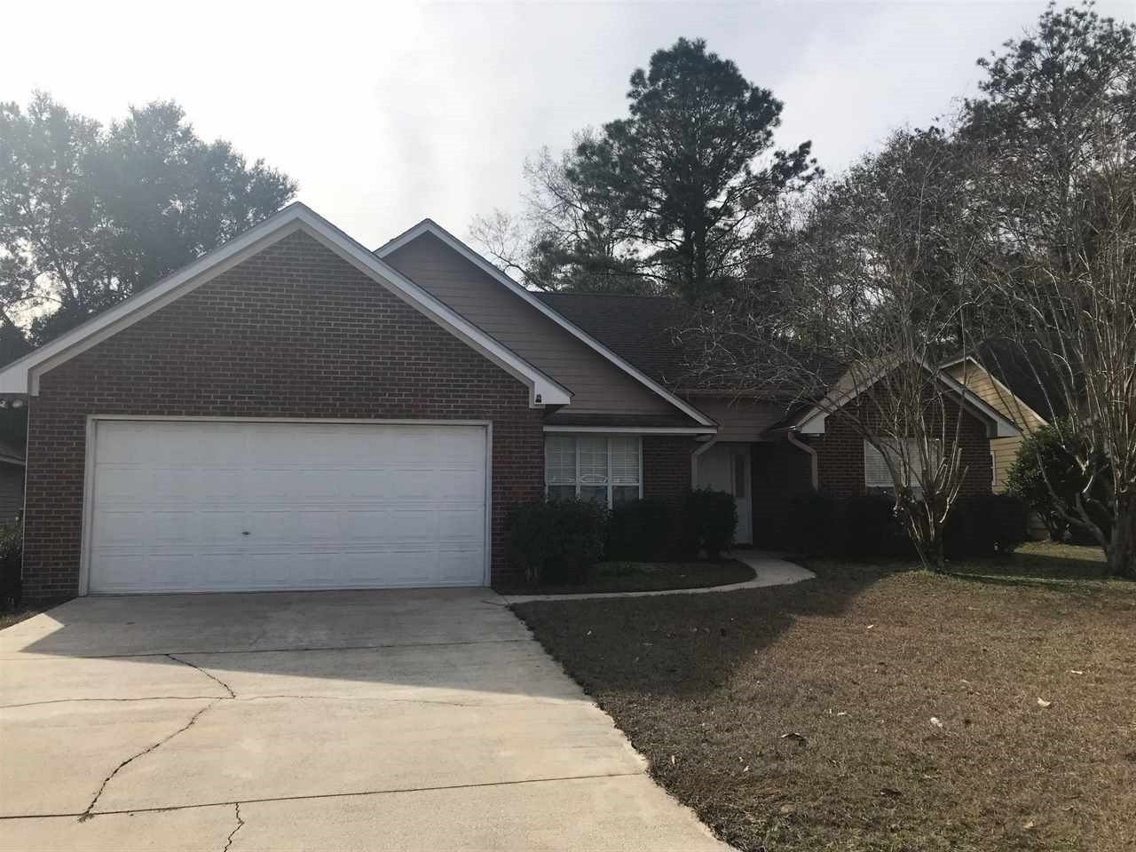 A brick home featuring a garage and a well-maintained driveway, showcasing a classic suburban aesthetic.