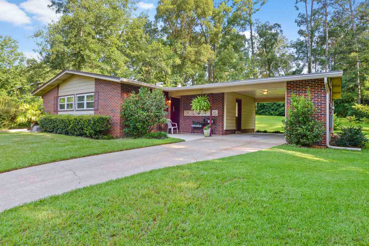 A brick home with a driveway surrounded by lush green grass.