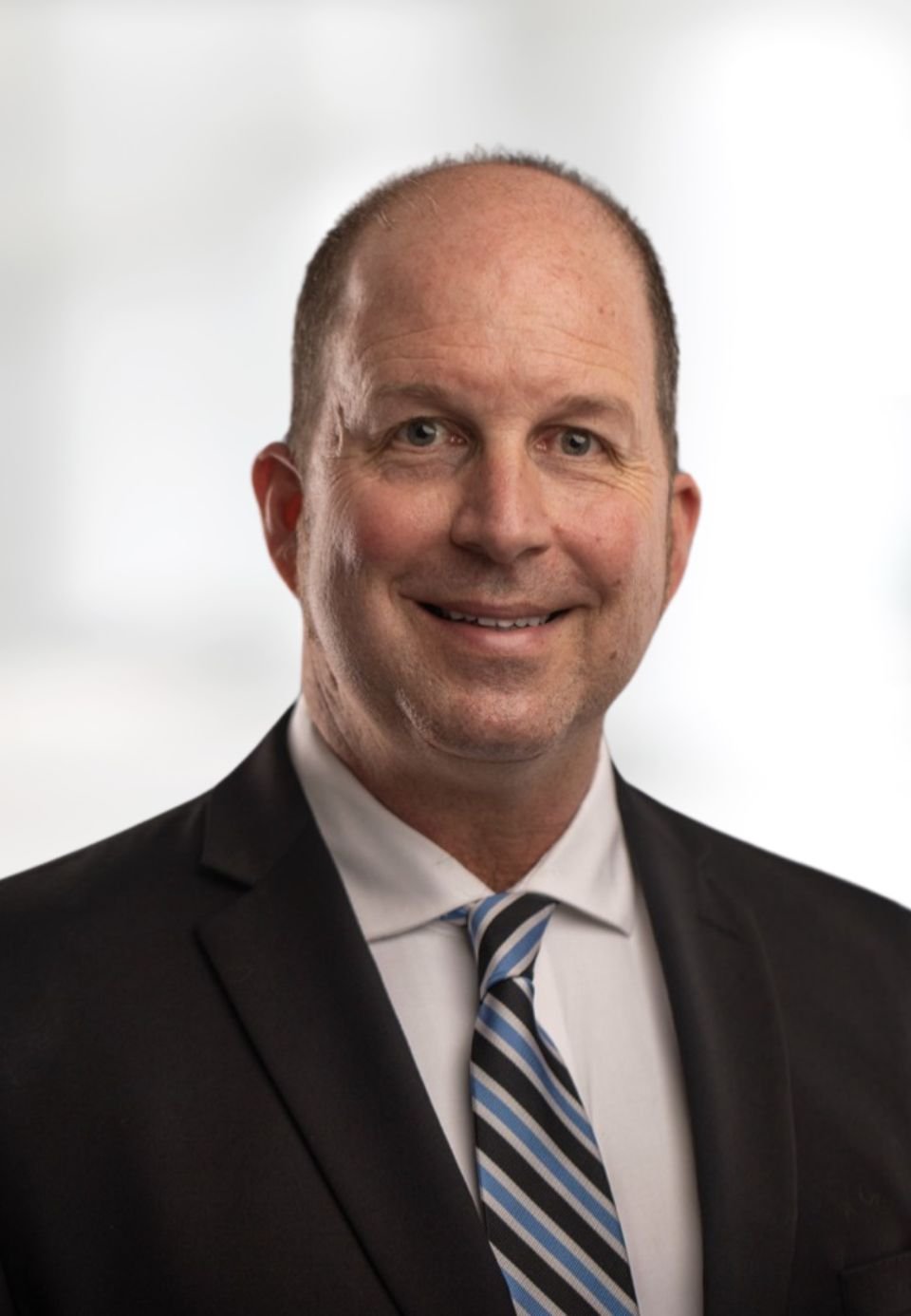 Bret Williams in a dark suit and blue striped tie