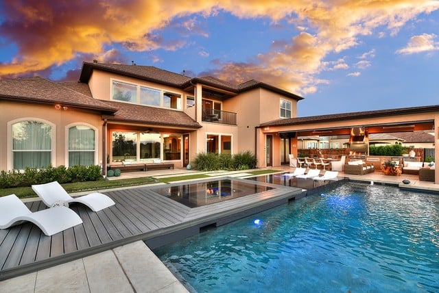 Luxury Texas home with modern backyard pool, sun deck, and outdoor living space at sunset, prepared for extreme summer heat