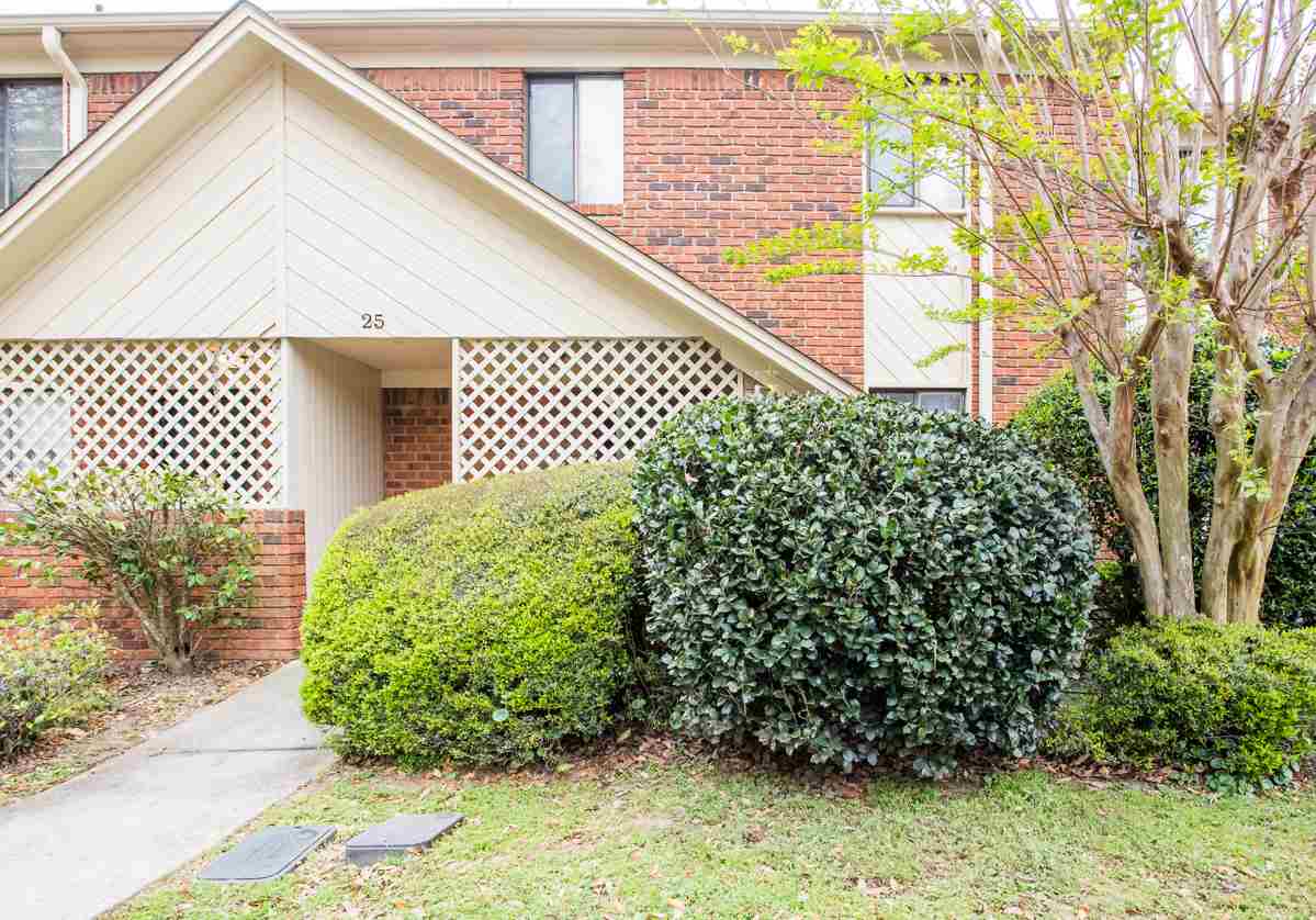 A brick apartment building surrounded by a well-maintained front yard, showcasing greenery and inviting entrance.