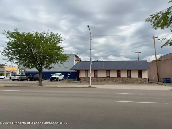 Single-story commercial building in Craig with a stone base and red-trimmed windows beside the street.