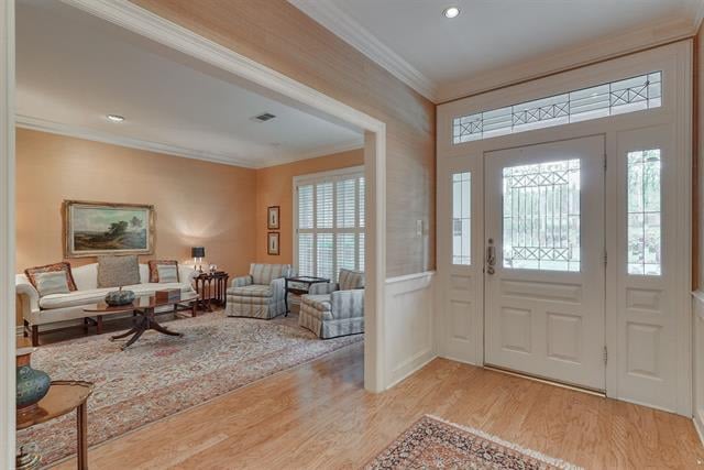 Entryway with a decorative glass front door, hardwood floors, and a view into the furnished living room.
