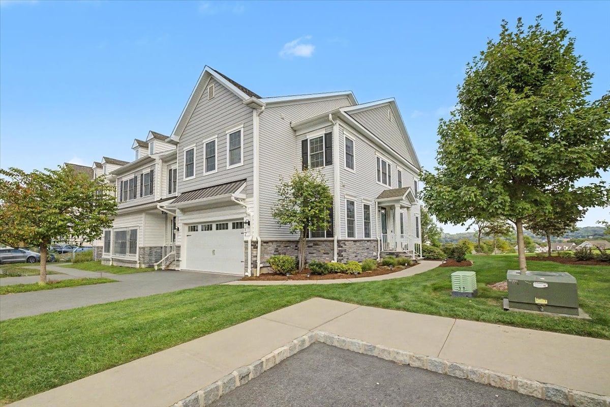 Light-gray multi-story building with an attached garage, stone accents, and landscaped grounds.