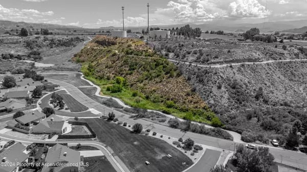 Aerial view of Rifle homes and curving roads beside a scrub-covered hillside.