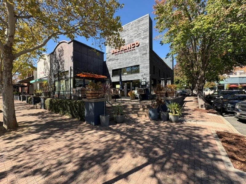 Barranco restaurant on a downtown sidewalk, with outdoor seating beneath mature trees.