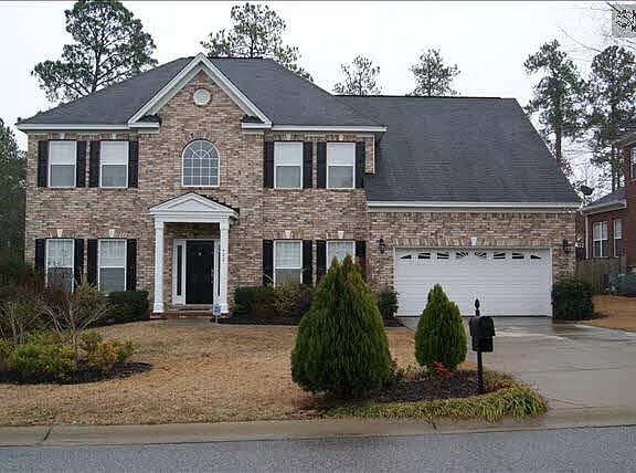 Two-story brick house with an attached white garage and front lawn.
