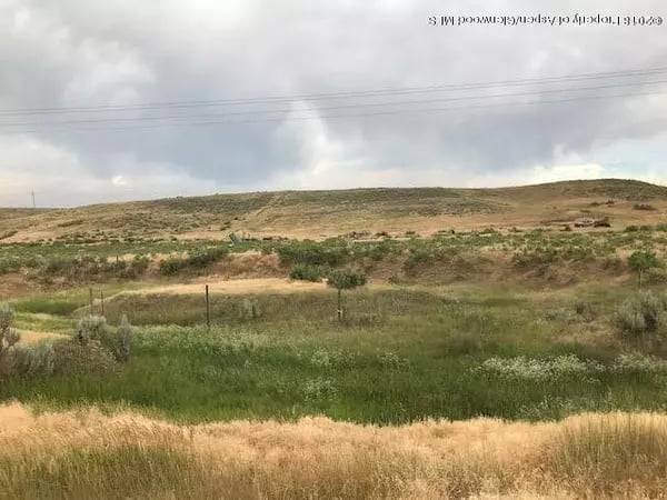 Rolling scrub-covered hills and grassy fields beneath a cloudy sky near Craig, Colorado.