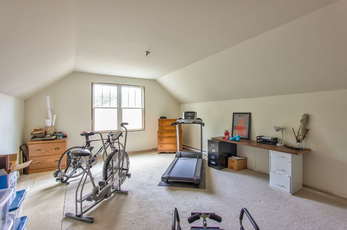 Bonus room with a treadmill and stationary bikes beneath a sloped ceiling.