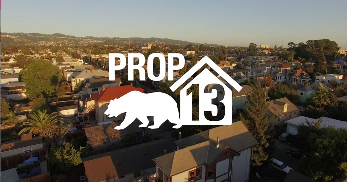 Prop 13 graphic over an aerial view of a suburban neighborhood.
