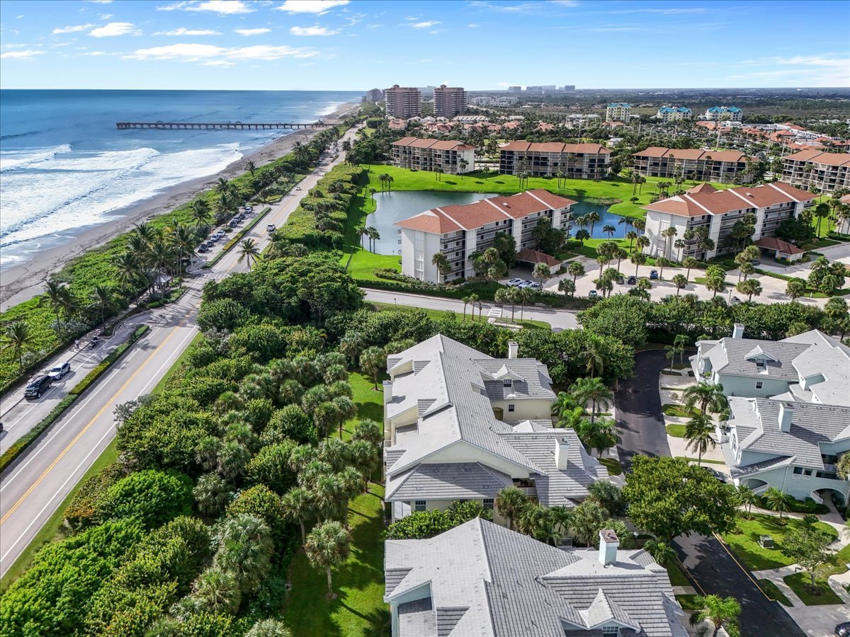 Aerial view of Sea Colony condominiums beside the ocean, with landscaped grounds and a pier along the shore.