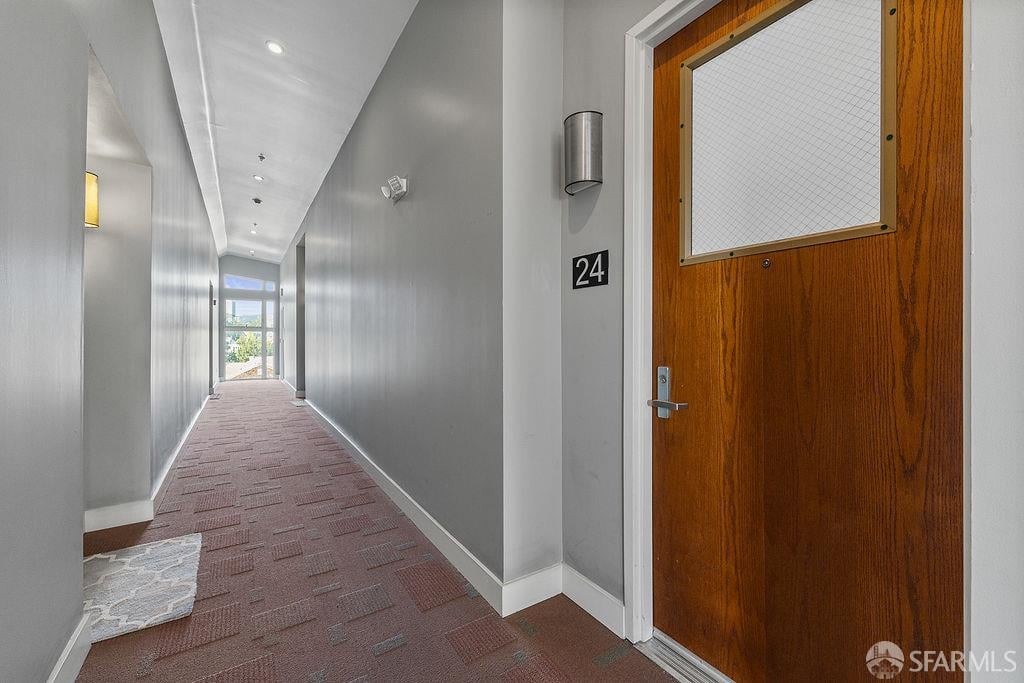 Apartment hallway with patterned carpet and a wood entry door marked 24.