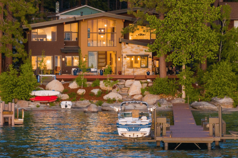 Lakefront home with a private dock and boat moored beside the shore at dusk.