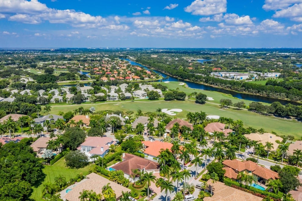 Aerial view of homes beside a golf course and winding canal.